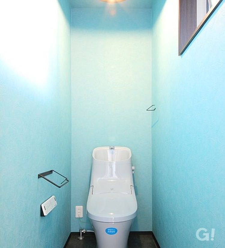 一面鮮やかなブルーの壁紙を使ったトイレ