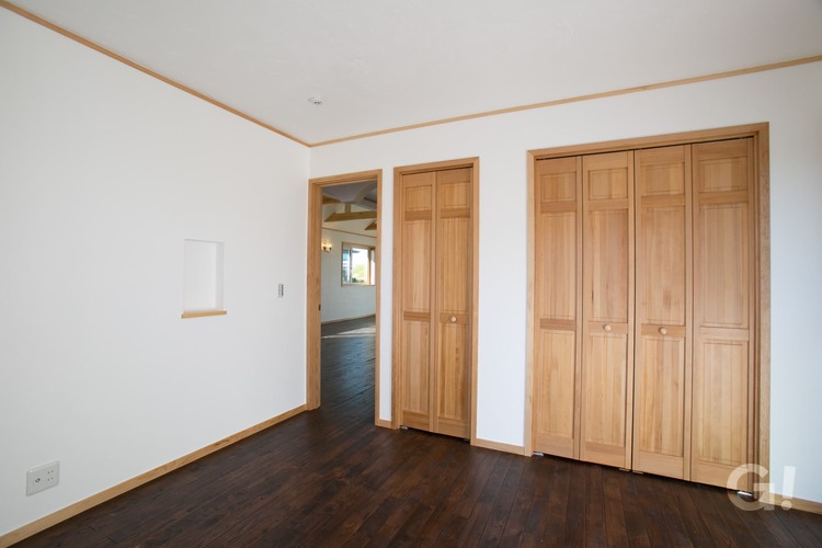 『木の扉が優しい雰囲気を届けてくれるクローゼット付きのシンプルモダンな洋室』の写真