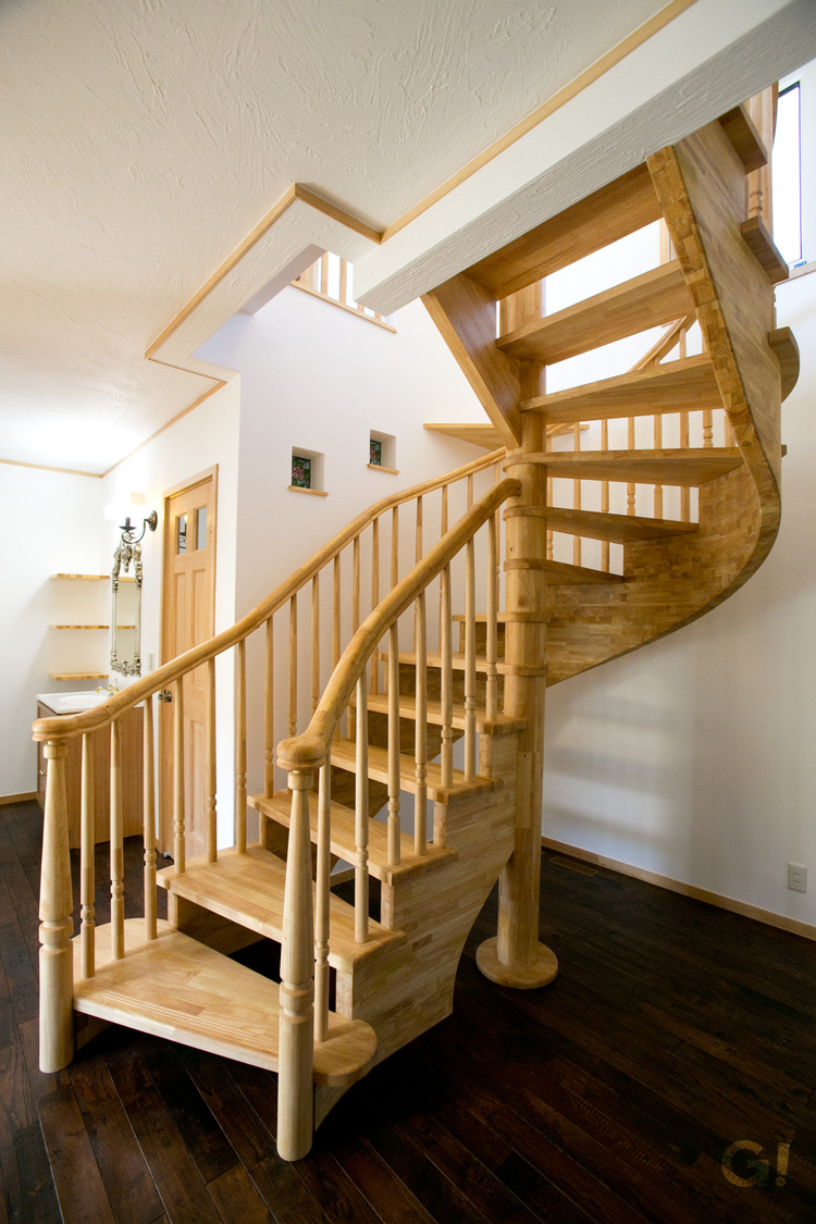 『美しい曲線と木の優しさ届くストリップ階段が存在感をあらわすシンプルモダンな1階ホール』の写真