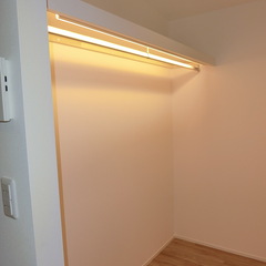 間接照明でやわらかく照らされるオープンタイプの収納があるシンプルモダンな洋室