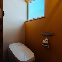 オレンジの塗り壁がアクセントになるトイレ／今治市「潜と珊瑚の家」