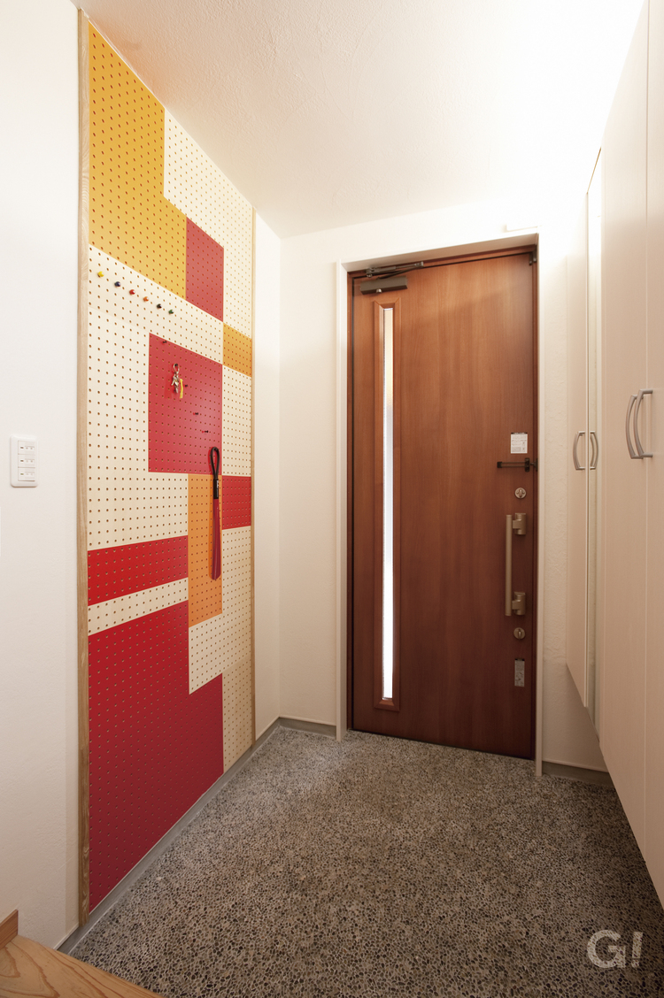 『壁をお洒落に有効活用！カラフルなデザインウォールが一際目を惹くシンプルモダンな玄関』の写真