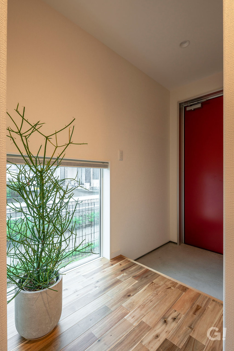 『赤いドアがお洒落ポイント！地窓から見える景色にホッと癒されるシンプルモダンな玄関』の写真