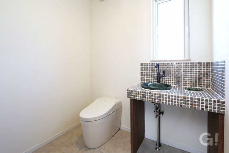 ハウスカが提案するシックな色味のタイルと洗面ボウルを使用したトイレ空間。