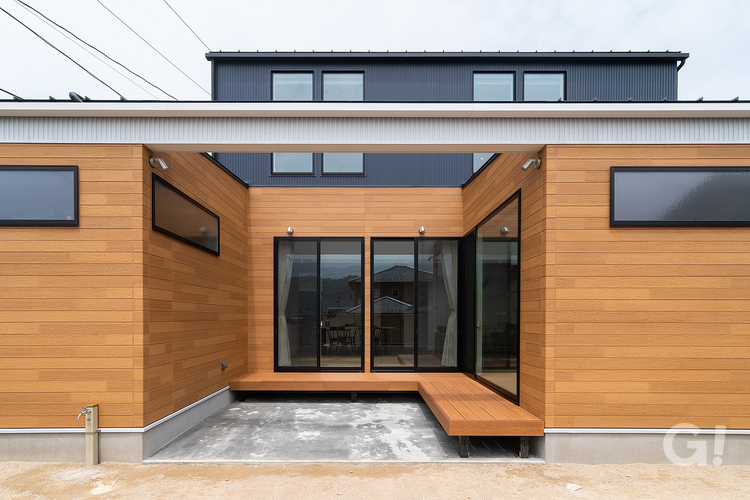 L字型のウッドデッキと黒の窓枠が映えるおしゃれなデザイン住宅