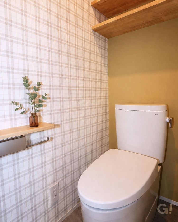 木の棚と落ち着いたカラークロスを採用した注文住宅のトイレ。シンプルなデザインと程よい収納で、清潔感のある快適なトイレ空間の施工事例