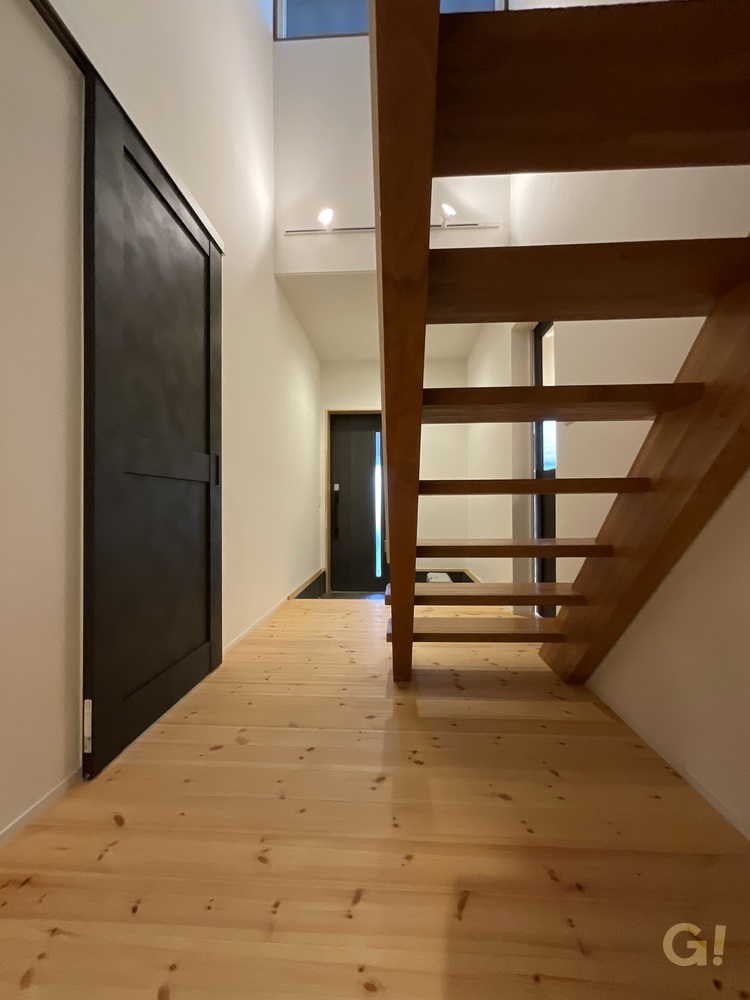 『木製ストリップ階段が素敵に存在をあらわすシンプルモダンな玄関ホール』の写真