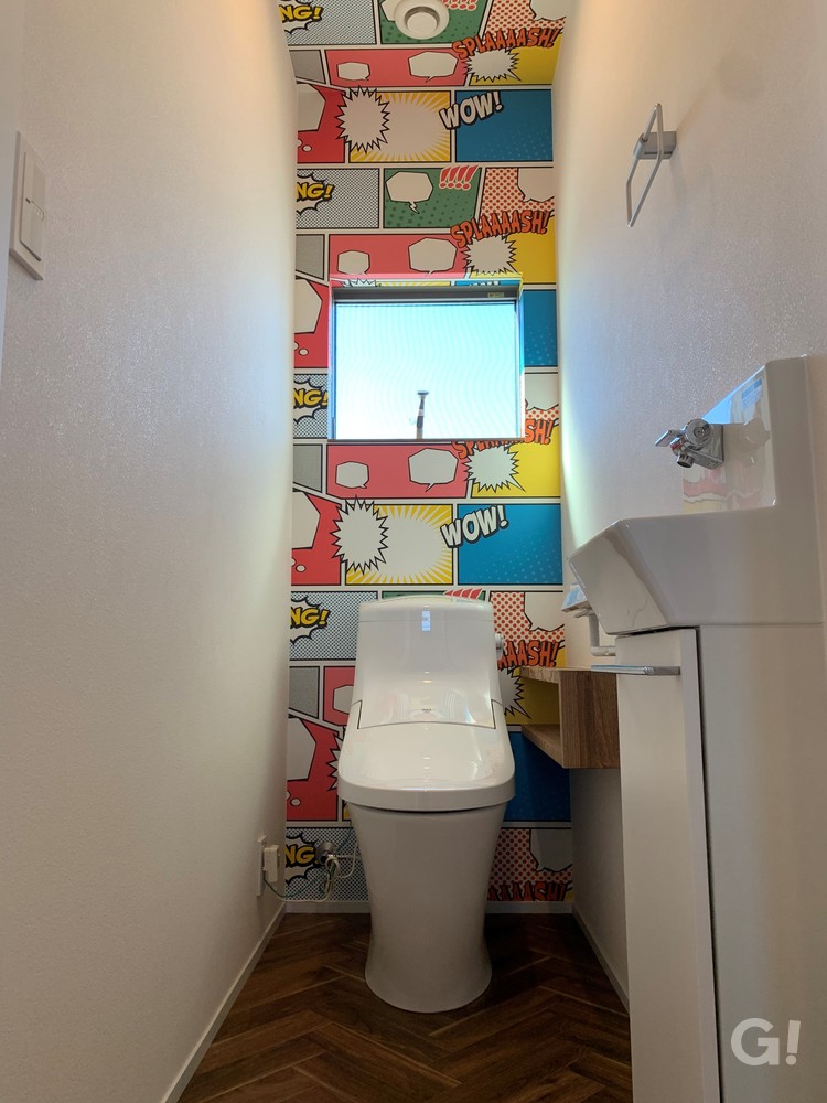 『ポップな色使いのクロスで心がウキウキ弾む楽しさ広がるアメリカンな家のトイレ』の写真