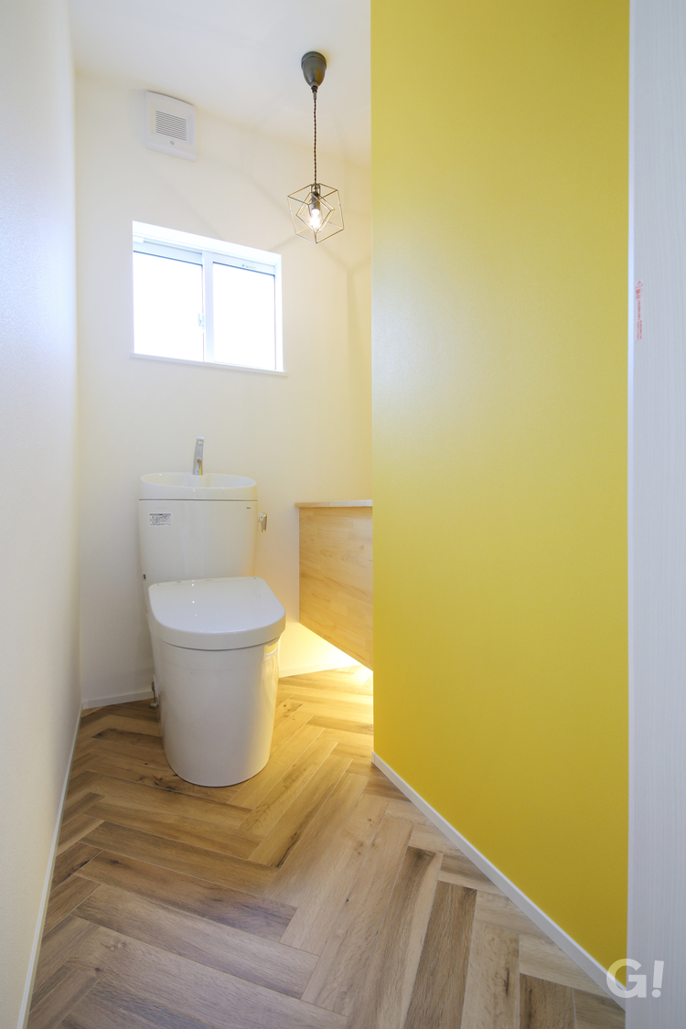 ヘリンボーンの床と黄色のクロスがかわいいトイレの写真