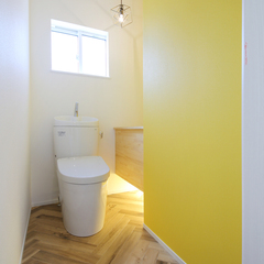 ヘリンボーンの床と黄色のクロスがかわいいトイレ