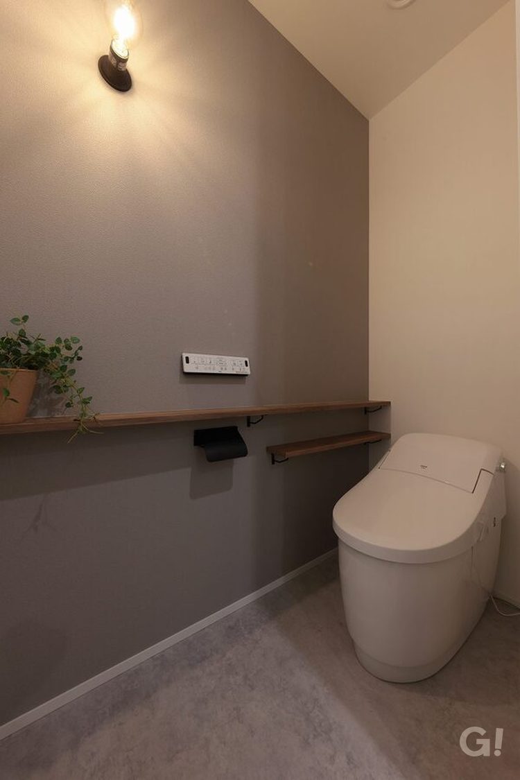 グレーのアクセントクロスと裸電球の壁付け照明のトイレ写真2