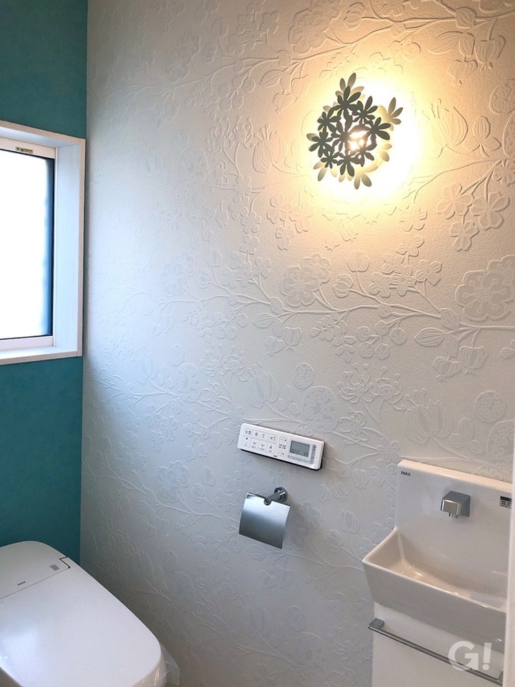 白い花柄のデザインクロスが浮かび上がるおしゃれなトイレ。足利市・福富住宅の注文住宅「音を奏でる家」