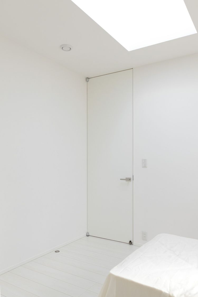 白い壁に一体化したシンプルな寝室のドア