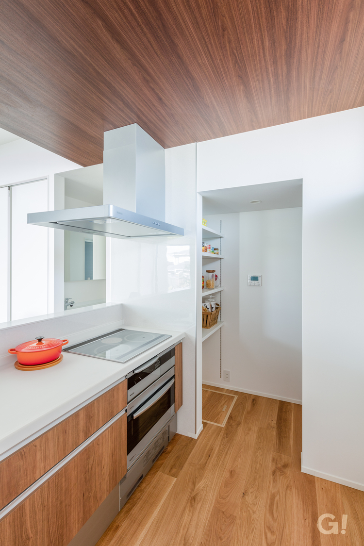 美しい規格住宅の清潔感あふれるキッチンと利便性抜群のパントリーの写真
