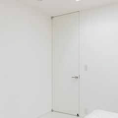 白い壁に一体化したシンプルな寝室のドア