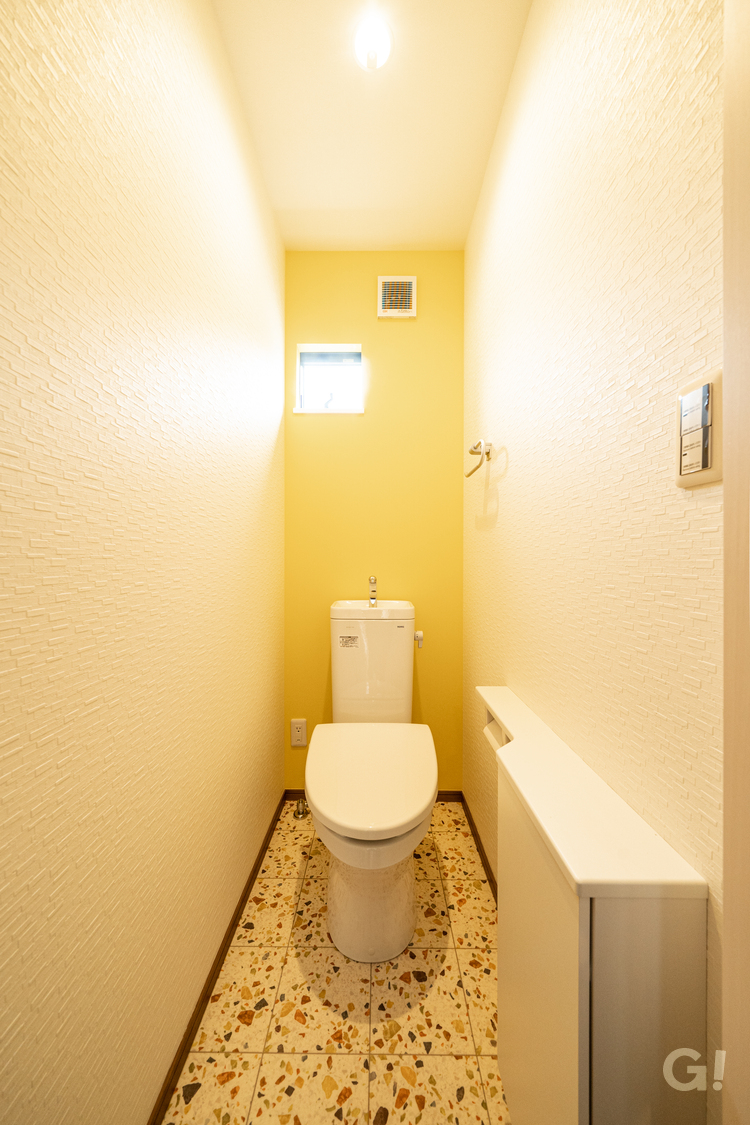 イエローカラークロスがかわいらしいお洒落なトイレの写真