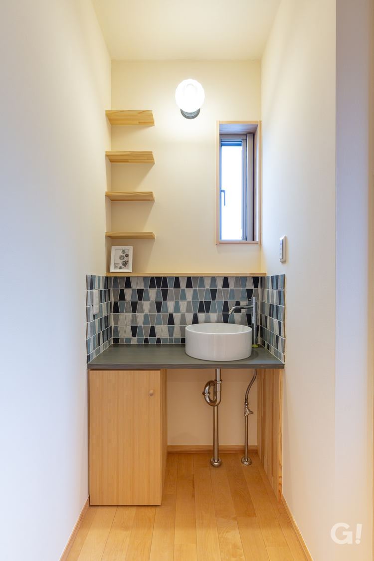 和モダン住宅に映えるタイルが目に留まる玄関先の洗面所空間