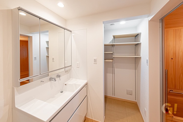 『大容量収納スペースへと繋がり使い勝手のいいシンプルモダンな洗面所』の写真