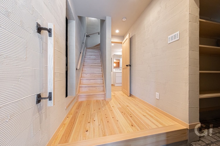 『無垢材の床がLDKまで優しく誘導してくれるシンプルモダンな玄関ホール』の写真