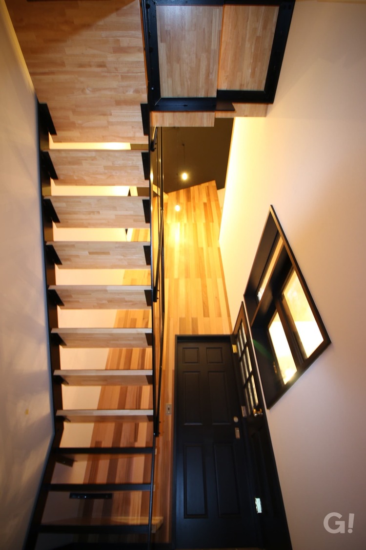 『存在感をあらわすストリップ階段から優しく光がもれるシンプルモダンな玄関ホール』の写真