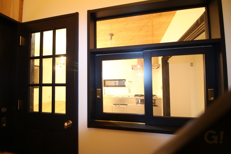 『黒でカッコいい室内窓からLDKの灯りが優しくもれるシンプルモダンな玄関ホール』の写真