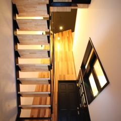 存在感をあらわすストリップ階段から優しく光がもれるシンプルモダンな玄関ホール