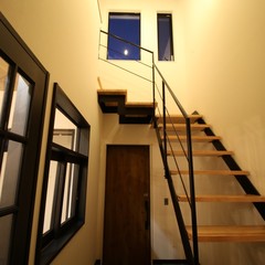 黒アイアン手すりのストリップ階段がかっこよく存在感をあらわすシンプルモダンな玄関ホール