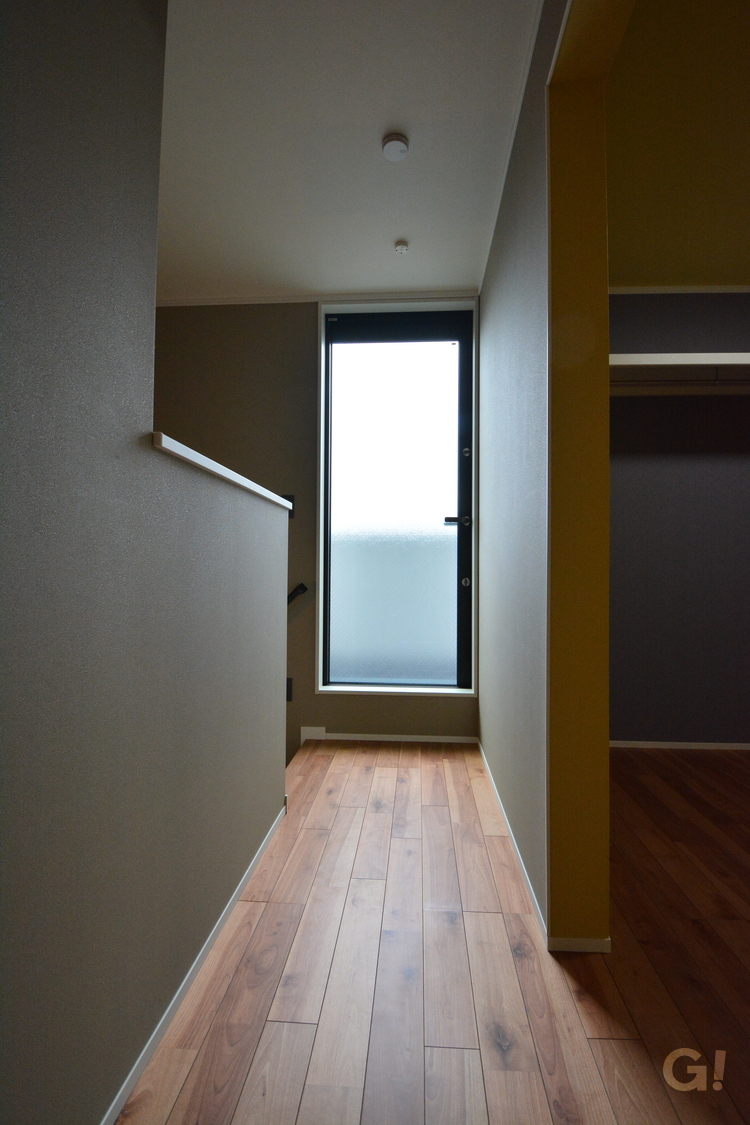 『ベランダへと直線に繋がる無垢の床からは優しい温もり伝わるナチュラルな家の2階廊下』の写真