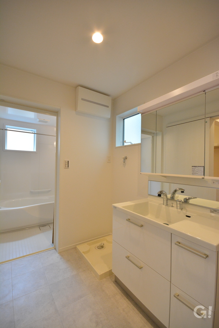 『清潔感のある白い空間！浴室へフラットに繋がる使い勝手のいいナチュラルな家の洗面室』の写真