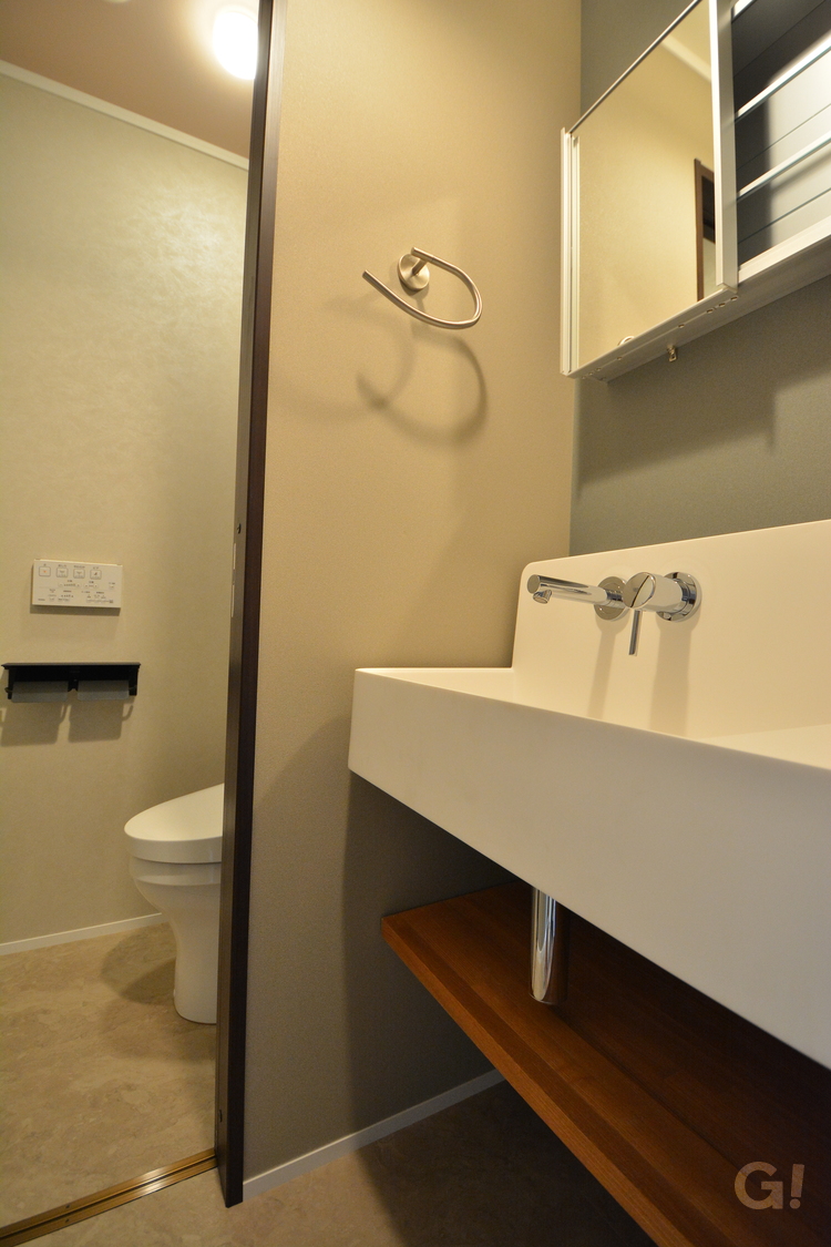 『トイレへフラットに繋がり生活動線抜群！アースカラーで心穏やかになるナチュラルな家の洗面室』の写真