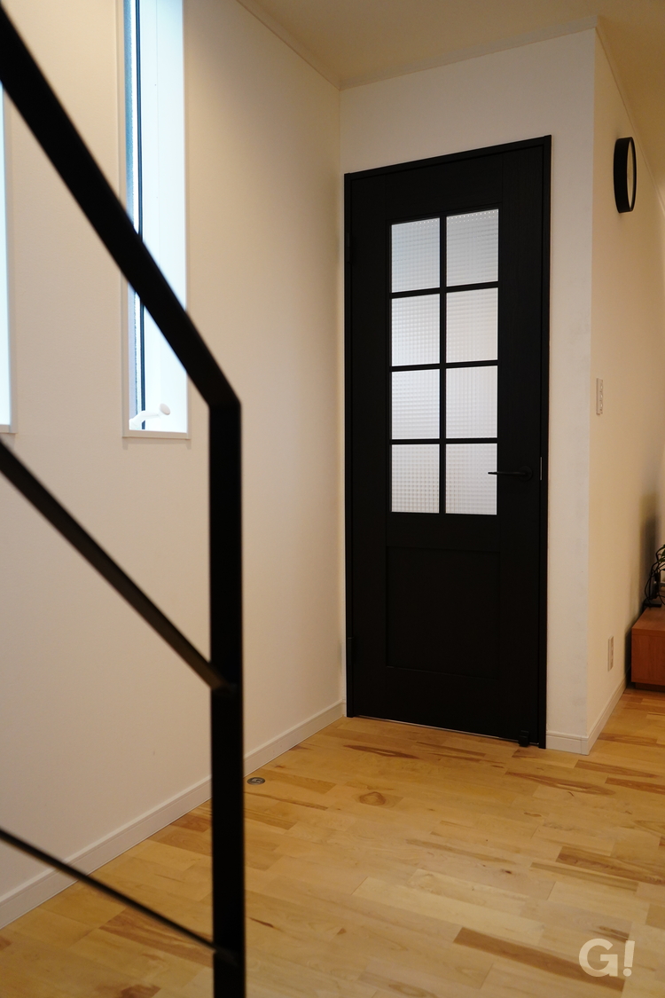 『深みのあるカッコいい黒いドアが空間を引き締めてくれるナチュラルな家のリビング』の写真