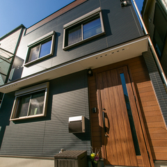 奥深さのあるダークグレーの外壁とナチュラルな玄関ドアが合うシンプルモダンな家