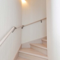 白い空間にブラケットライトが美しく光り輝くナチュラルな家の階段