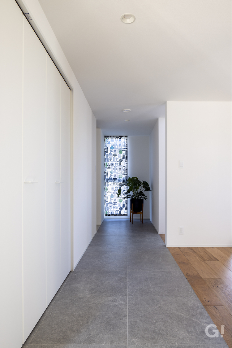 真っ直ぐ伸びるグレーのタイル床が上品に誘導してくれるシンプルモダンな廊下