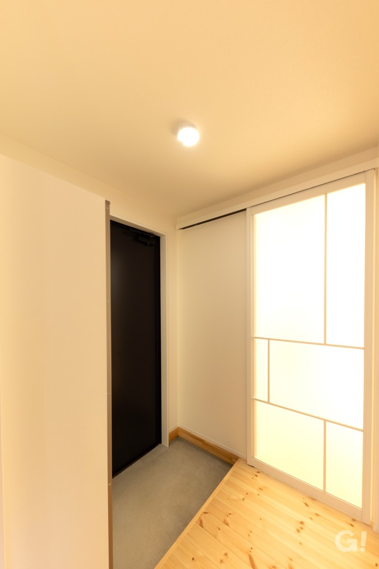 明るい日差しを通すオシャレな半透明扉のある玄関ホールの写真