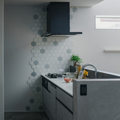 キッチンの壁にはデザイン性だけでなく、油などの汚れ防止効果もあるグレイッシュトーンのハニカムタイルを使用