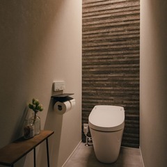 石目模様のアクセントウォールと間接照明で雰囲気のあるトイレ