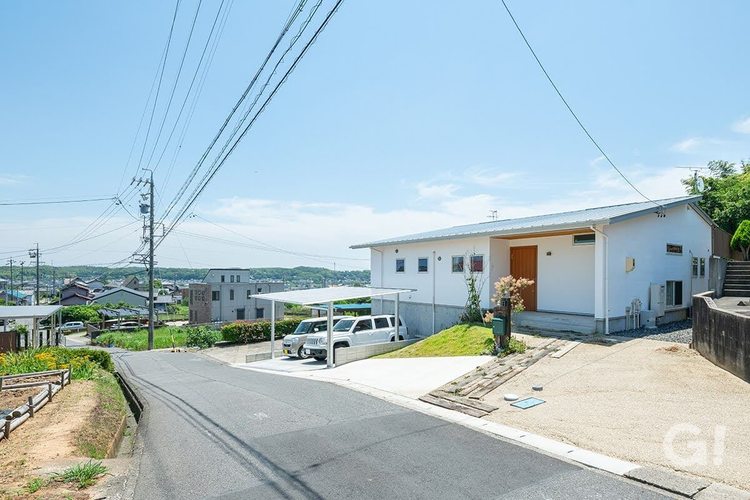 高台に建つ漆喰の外壁の平屋