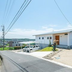 高台に建つ漆喰の外壁の平屋